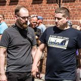 Links auf dem Bild sehen wir wieder einen Nipster: Designer-Bart und dicke Kastenbrille. Der Styler könnte auch in einem angesagten Social Startup im Prenzlauer Berg PR-Kampagnen für Seenotrettung entwerfen. Das wird er aber ganz sicher nicht tun. Denn es handelt sich bei dem Nazi-Hipster um den Identitären Robert Timm, der sich vor allem vor Überfremdung in Europa durch Migranten fürchtet. Diese völkische Kümmernis bringt er hier 2019 auf einer Demo der "Identitären Bewegung" in Sachsen-Anhalt  zum Ausdruck. Dieselben Überfremdungsängste thematisiert auch sein Identitären-Kamerad Daniel Fiss rechts neben ihm unter Zurhilfenahme seines T-Shirt-Aufdruckes. Als stilbewusster Nipster trägt Timm allerdings keine Motiv-Shirts, sondern ein Polohemd von Fred Perry. Die Marke wurde bei Rechtsextremen vor allem wegen ihres Logos beliebt, das einen stilisierten Siegerkranz zeigt, der Rechtsextremen auf der ganzen Welt wohl irgendwie genuin faschistisch zu sein scheint. In den USA wählten die rechtsextremen "Proud Boys" die Hemden von Fred Perry sogar als ihre offizielle Uniform aus. Viele davon erstürmten darin 2021 das Kapitol in Washington. Erfreulicherweise erwarteten sie dann keine Lorbeerkränze, sondern saftige Haftstrafen.
