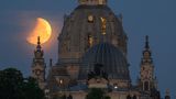 Roter Mond steht über der Dresdener Frauenkirche sowie über der Kuppel der  Kunstakademie