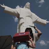 Eine Frau und ihre Tochter stehen vor Christusstatue beobachten die Sonnenfinsternis mit selbst gemachten Sonnenschutzmitteln.