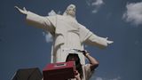 Eine Frau und ihre Tochter stehen vor Christusstatue beobachten die Sonnenfinsternis mit selbst gemachten Sonnenschutzmitteln.