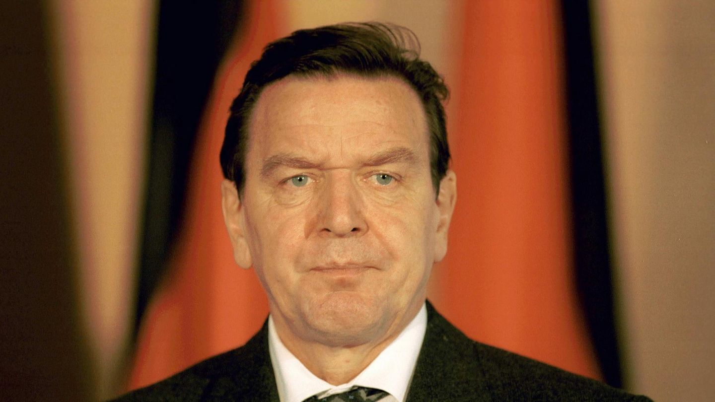 Gerhard Schröder steht mit ernster Mine vor einer Deutschland-Flagge Gerhard Schröder steht mit ernster Mine vor einer Deutschland-Flagge