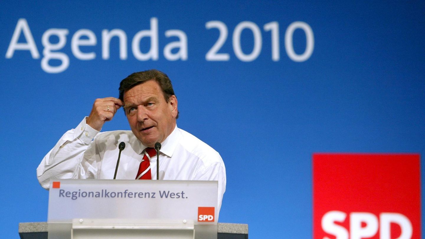 Gerhard Schröder steht am Rednerpult vor einer blauen Wand mit weißem "Agenda 2010"-Schriftzug