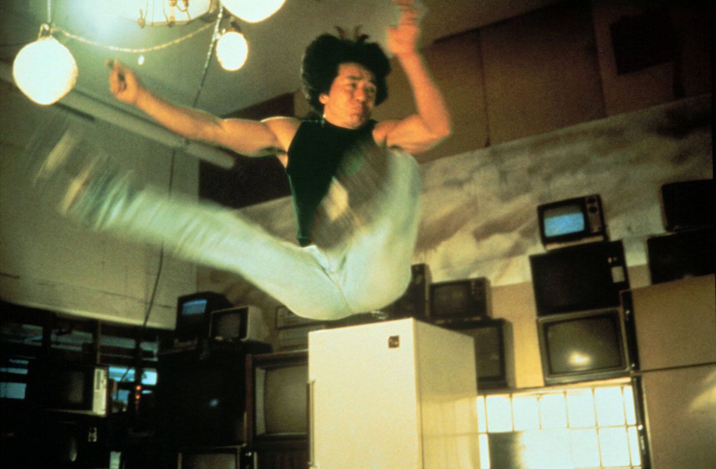 Jackie Chan springt mit im 90-Grad-Winkel angehobenen Beinen in die Luft Jackie Chan springt mit im 90-Grad-Winkel angehobenen Beinen in die Luft