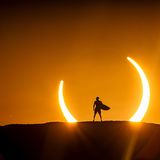 Mann mit Surfbrett vor Sonnenfinsternis