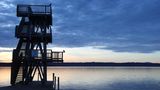 Im Morgenlicht steht ein hölzerner Sprungturm am Ammersee