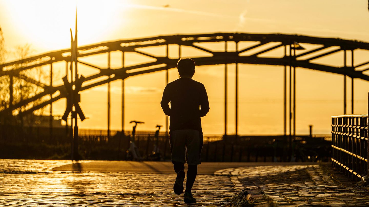 Im Morgenlicht läuft ein Mann über Kopfsteinpflaster auf eine Brücke zu