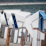 Weiße Strandkörbe mit schwarzen Nummern und blau-weiß gestreiften Polstern stehen am Ostseestrand