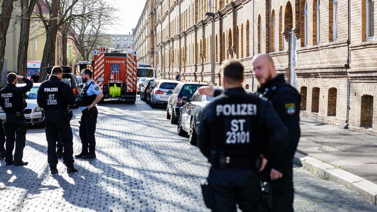 Polizisten und Feuerwehrleute stehen vor einem Wohnhaus in Halle an der Saale
