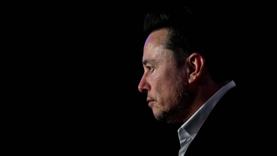 Elon Musk, vor dunklem Hintergrund, blickt nach links