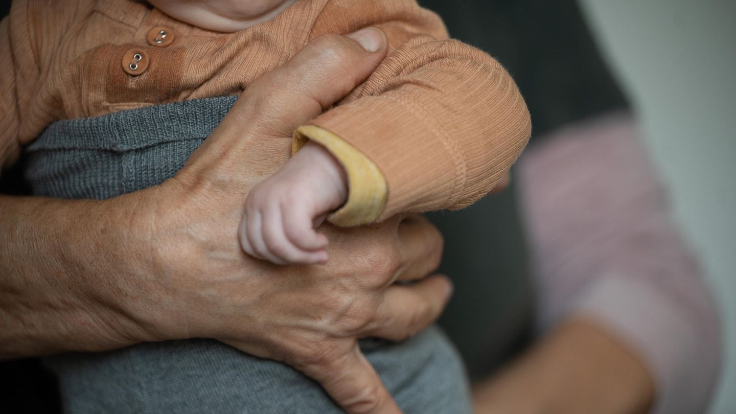 Eine ältere Person hält ein Baby im Arm