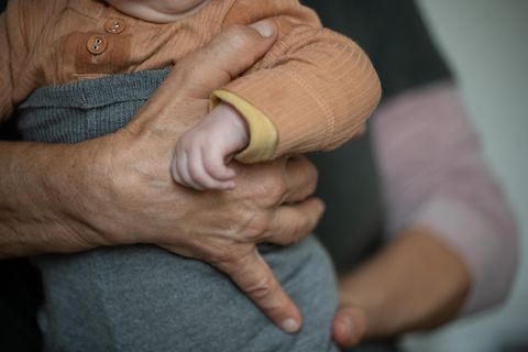Eine ältere Person hält ein Baby im Arm