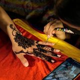 Eine Kosmetikerin verziert mit Henna die Hand einer Kundin mit traditionellen Mustern in Vorbereitung auf das bevorstehende Eid al-Fitr-Fest auf einem Markt in Lahore, Pakistan. Eid al Fitr markiert das Ende des islamischen heiligen Monats Ramadan