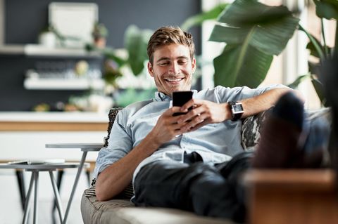 Mann liegt auf dem Sofa mit Galaxy S24 Ultra in der Hand.