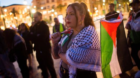 Teilnehmerin einer Demo mit Palästinenserschal und palästinensischer Flagge