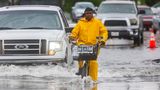 Ein Radfahrer fährt auf einer überfluteten Straße während eines schweren Gewitters