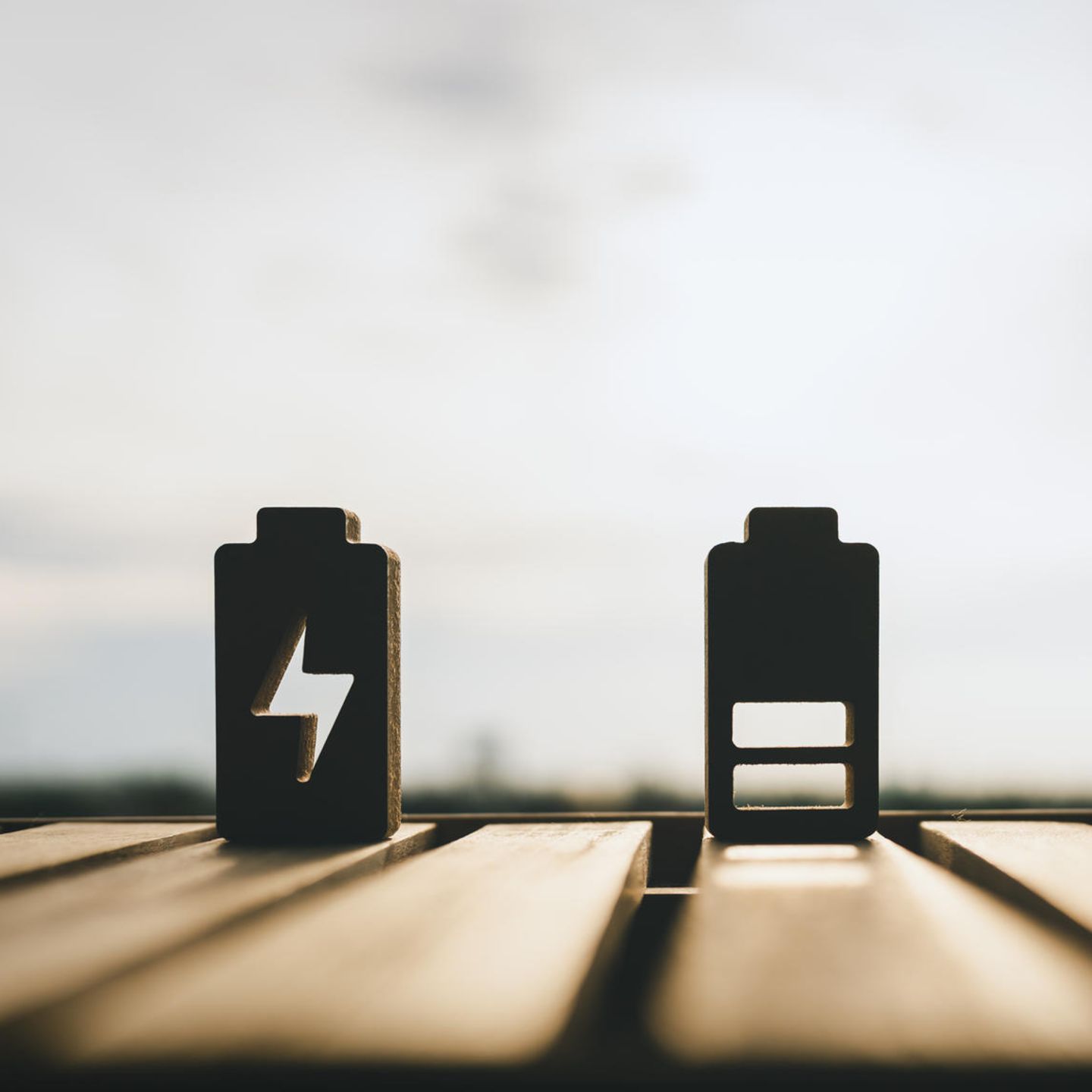 Speicher von Sonnenenergie – drei nachgebildete Batterien im Lademodus stehen in der Sonne.