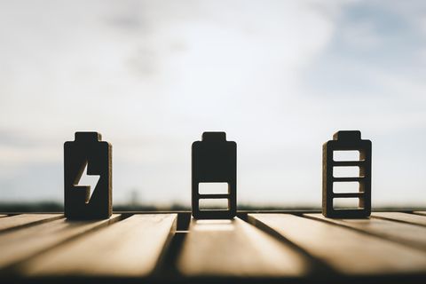 Speicher von Sonnenenergie – drei nachgebildete Batterien im Lademodus stehen in der Sonne.