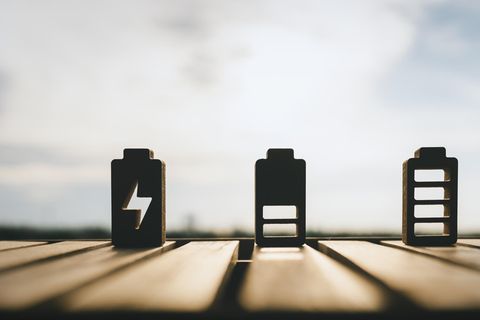 Speicher von Sonnenenergie – drei nachgebildete Batterien im Lademodus stehen in der Sonne.