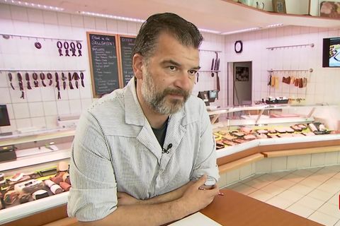 Ein Metzger steht vor seiner Fleisch-Theke