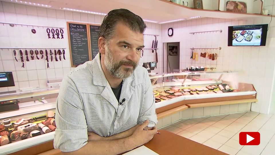 Ein Metzger steht vor seiner Fleisch-Theke