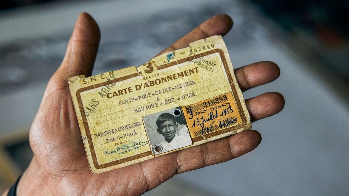 Ein Mann hält einen sehr alten vergilbten Ausweiß in der Hand darauf ein s/w Bild eines kleinen Jungen