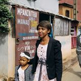 Eine Mutter läuft mti ihrer kleinen Tochter eine Straße entlang hinter ihr ein älterer Herr im grauen Anzug