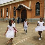 Mädchen spielen/tanzen vor einer Kirche in hübschen weißen Kleidchen