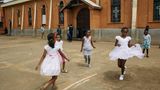 Mädchen spielen/tanzen vor einer Kirche in hübschen weißen Kleidchen