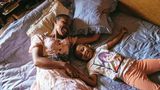 Eine Mutter und ihre Tochter liegen im Bett und lachen und kuscheln