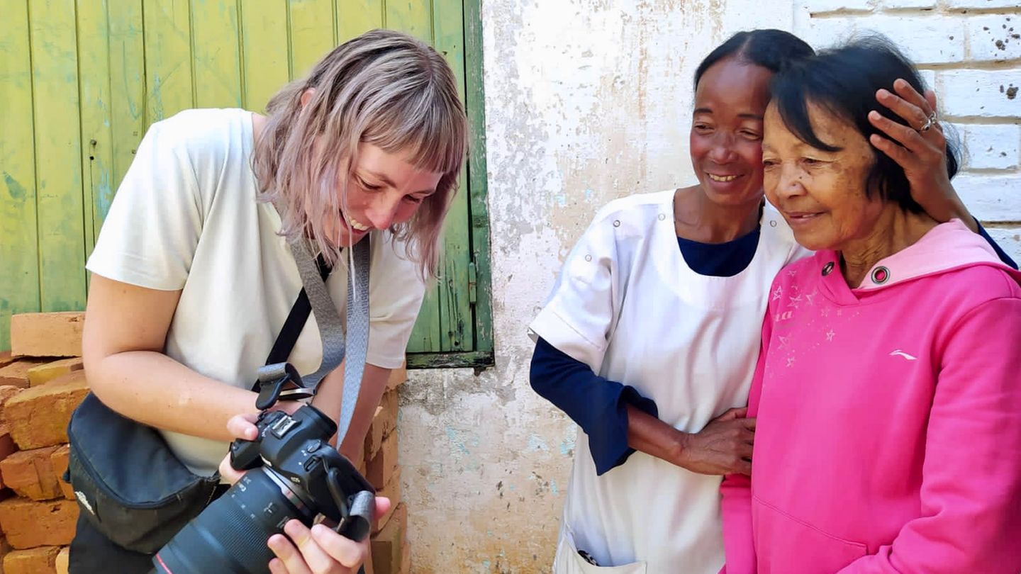 Fotografin Lee-Ann Olwage zeigt zwei Frauen ein Foto, das sie von ihnen gemacht hat, beide lächeln