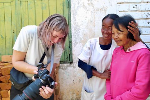 Fotografin Lee-Ann Olwage zeigt zwei Frauen ein Foto, das sie von ihnen gemacht hat, beide lächeln