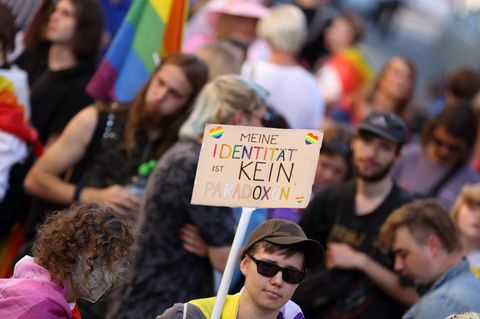 Ein Mensch hält ein Schild mit der Aufschrift: "Meine Identität ist kein Paradoxon" hoch