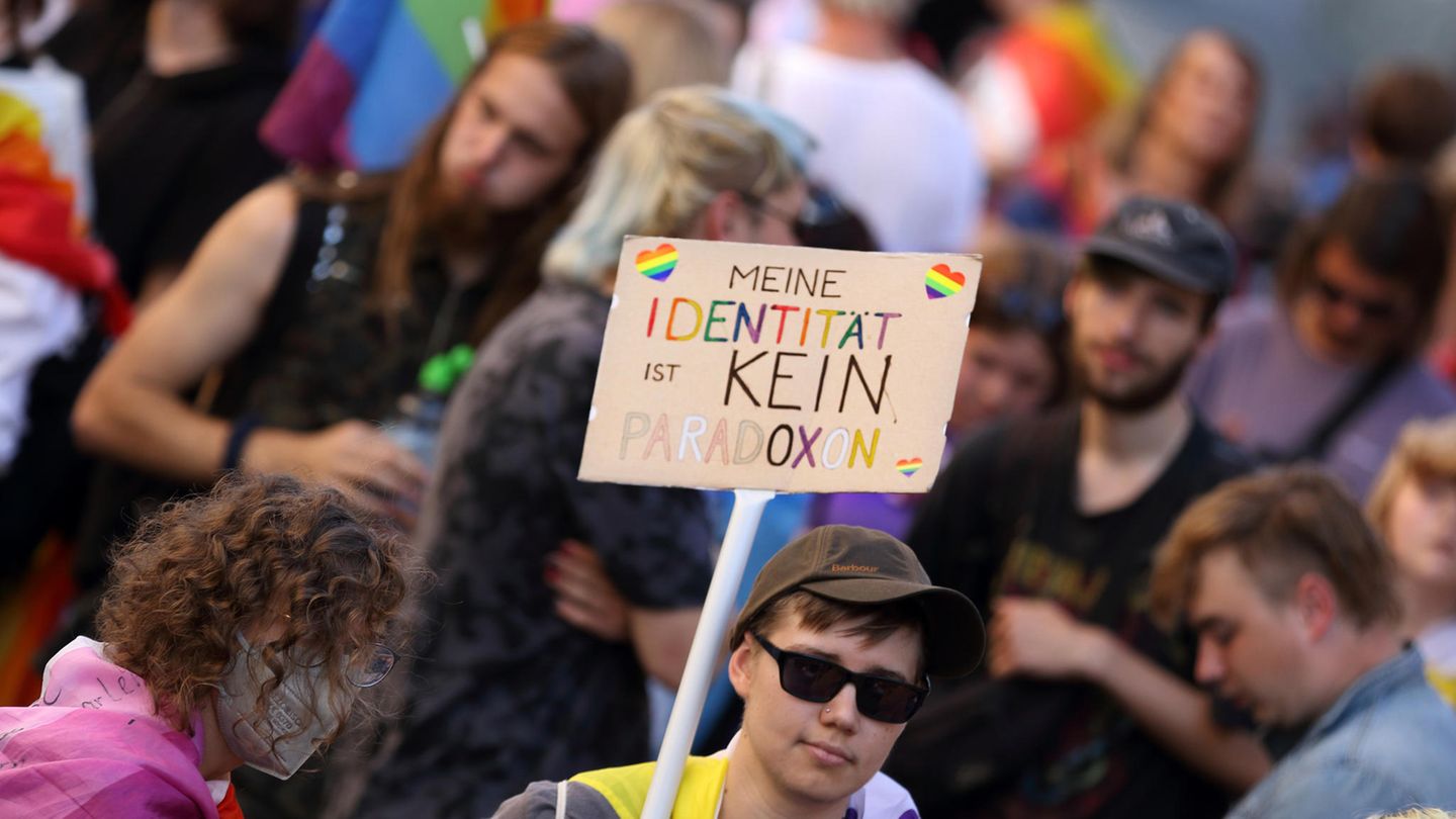 Ein Mensch hält ein Schild mit der Aufschrift: "Meine Identität ist kein Paradoxon" hoch