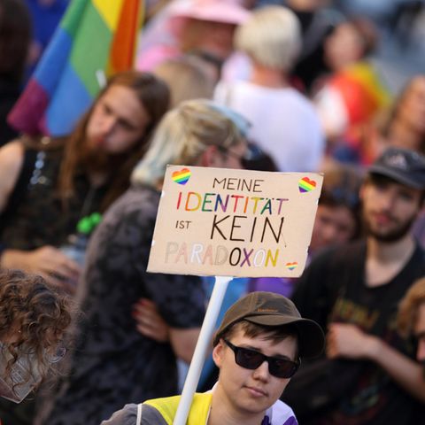 Ein Mensch hält ein Schild mit der Aufschrift: "Meine Identität ist kein Paradoxon" hoch