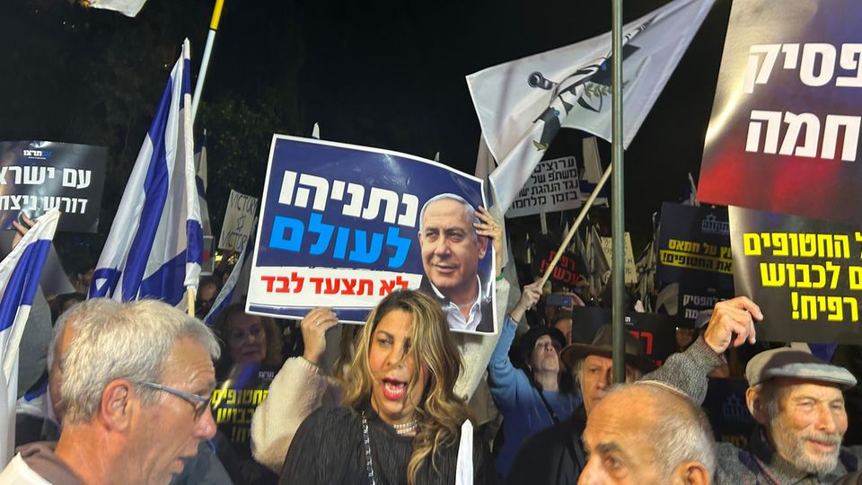 Hinter der Geschichte: "Netanjahu für immer. Du wirst nie alleine gehen" steht auf dem Schild einer Demonstrantin in Jerusalem "Netanjahu für immer. Du wirst nie alleine gehen" steht auf dem Schild einer Demonstrantin in Jerusalem