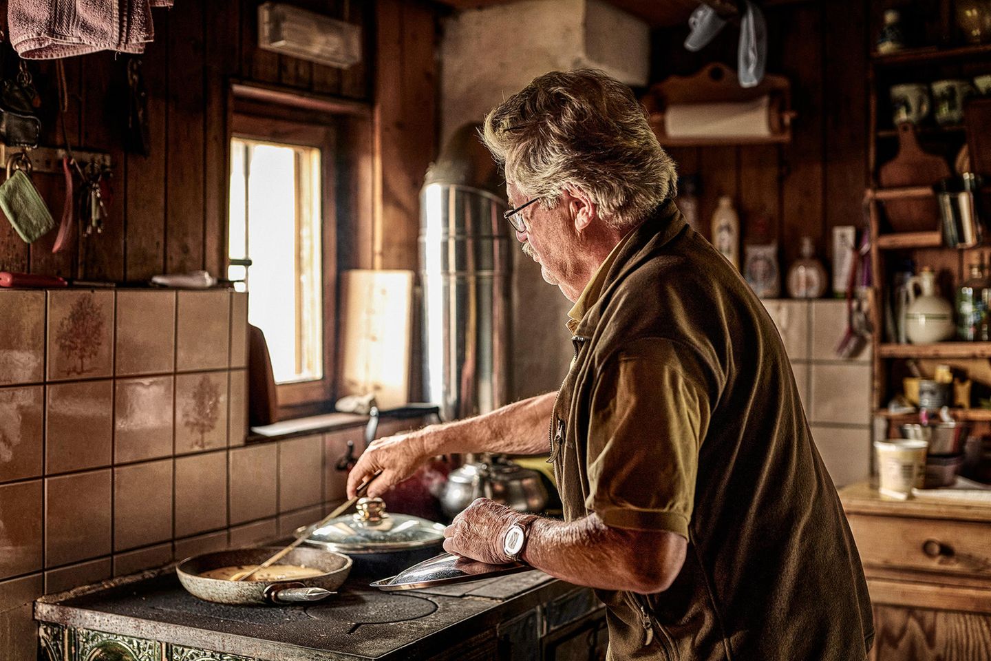 Ein Mann steht am Herd und macht Kaiserschmarn in einer Pfanne