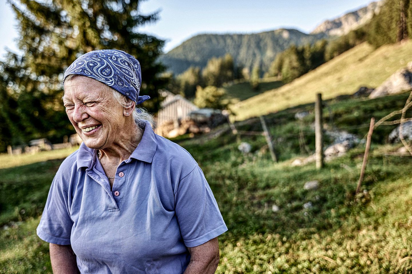 Ältere Sennerin steht vor ihrem Alm