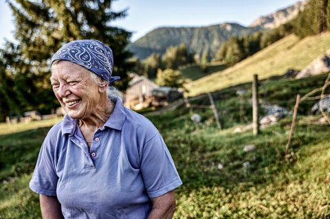 Ältere Sennerin steht vor ihrem Alm
