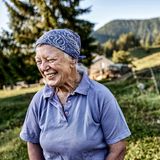 Ältere Sennerin steht vor ihrem Alm