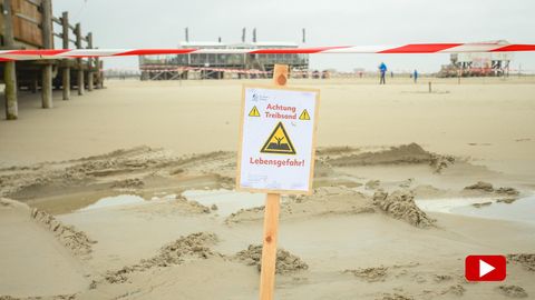 Ein Warnschild mit der Aufschrift: "Achtung Treibsand Lebensgefahr!" steckt im Sand am Strand in St. Peter-Ording an der Nordsee
