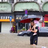 Ein Mann trägt ein kleines Mädchen auf den Schultern durch die Fluten in Guangzhou