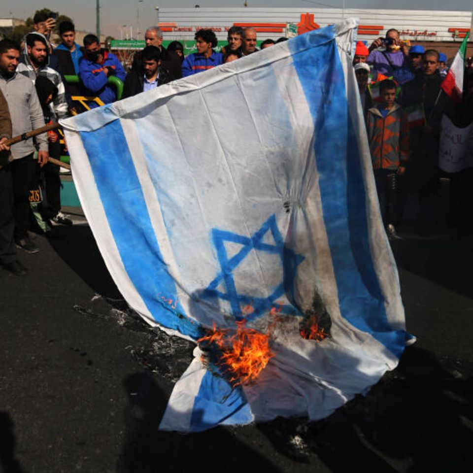 Menschen im Iran verbrennen eine Flagge Israels
