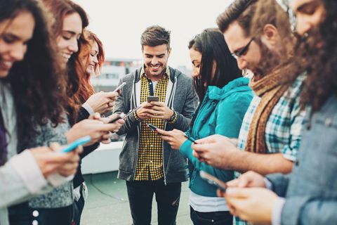 Gruppe von Freunden steht zusammen, jeder schaut auf sein Handy und freut sich über neue Deals ohne Anschlusspreis.
