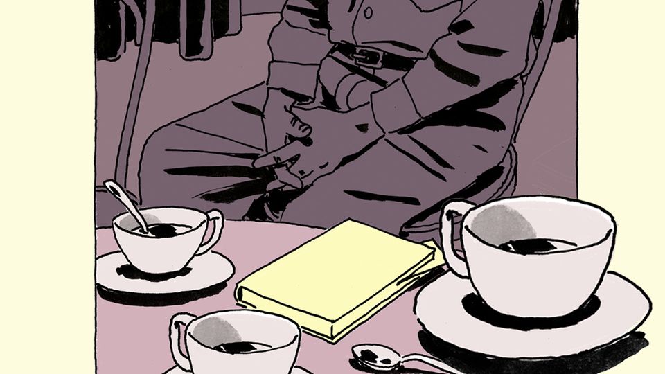 Ein älterer Mann sitzt an einem Tisch mit Kaffeetassen und einem Buch