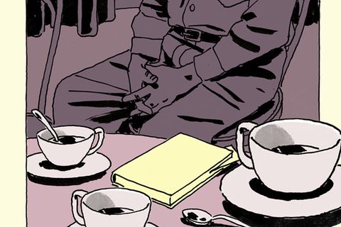 Ein älterer Mann sitzt an einem Tisch mit Kaffeetassen und einem Buch