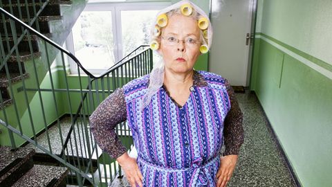 Bild einer älteren meckernden Frau mit Lockenwinklern im Treppenhaus