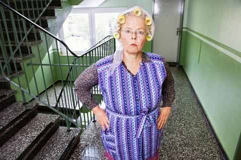 Bild einer älteren meckernden Frau mit Lockenwinklern im Treppenhaus
