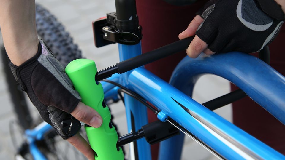 Mit Fahrradschlössern Rad sichern: Mann schließt sein Fahrrad mit einem Bügelschloss ab.