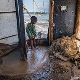 ein Kind in der Tür eines vom Wasser gefluteten Hauses