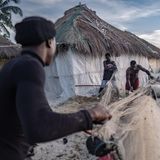 Fischer bereiten ihre Netze für den Fang auf, im Hintergrund prallen die Wellen gegen die Häuserfassaden